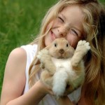 Blondes Mädchen hält kleines Kaninchen hoch